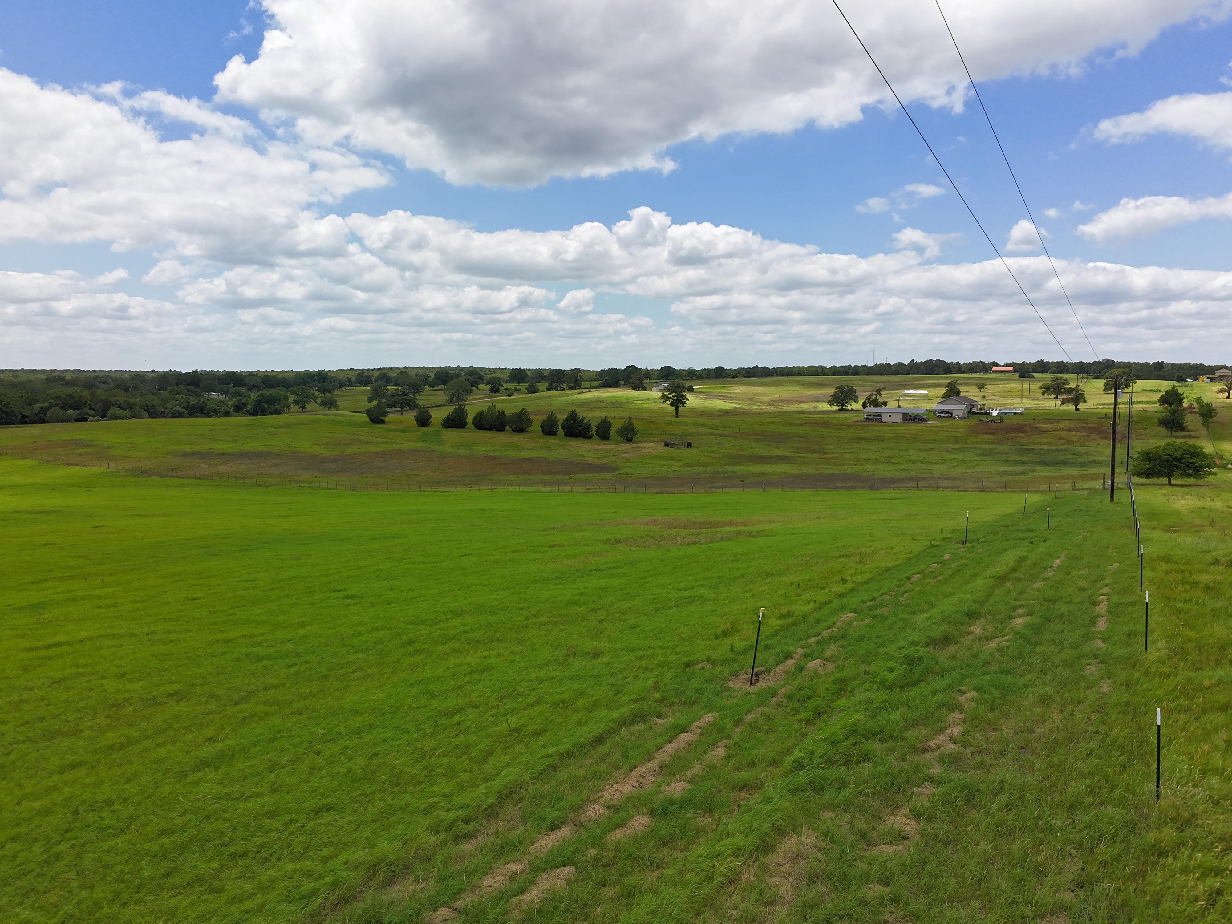 Drone view looking across the back of the property toward the tree line and neighboring farms