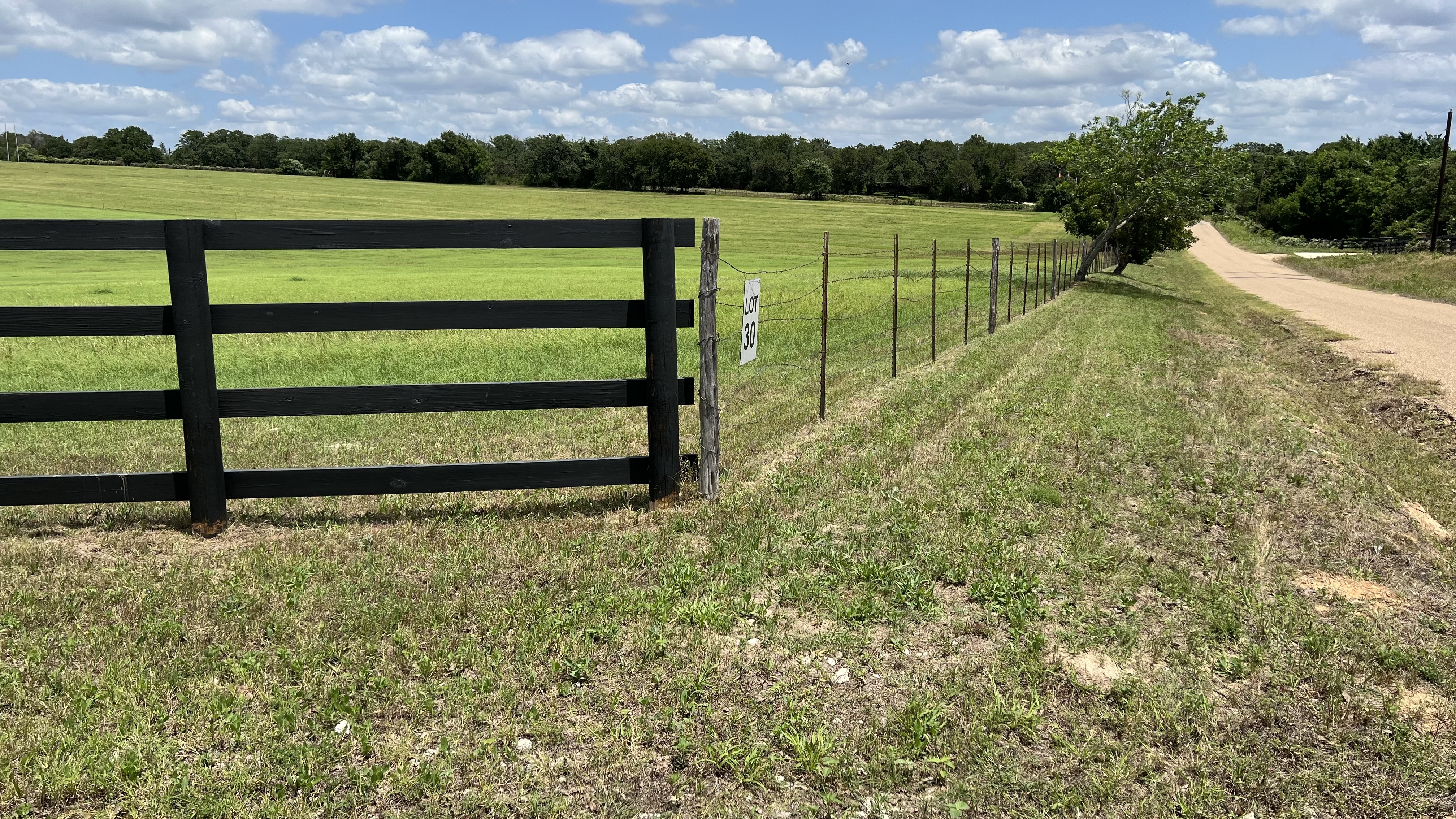 Paved county road frontage with black board fence